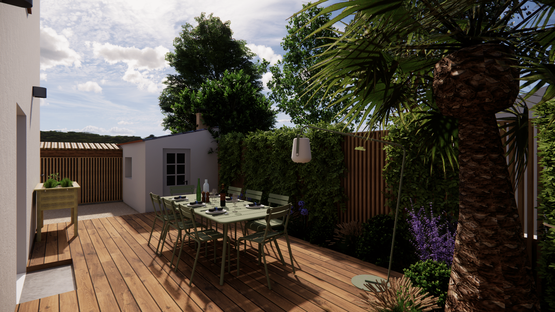Espace repas extérieur avec table verte sur terrasse en bois, entouré de verdure et d'un palmier exotique.